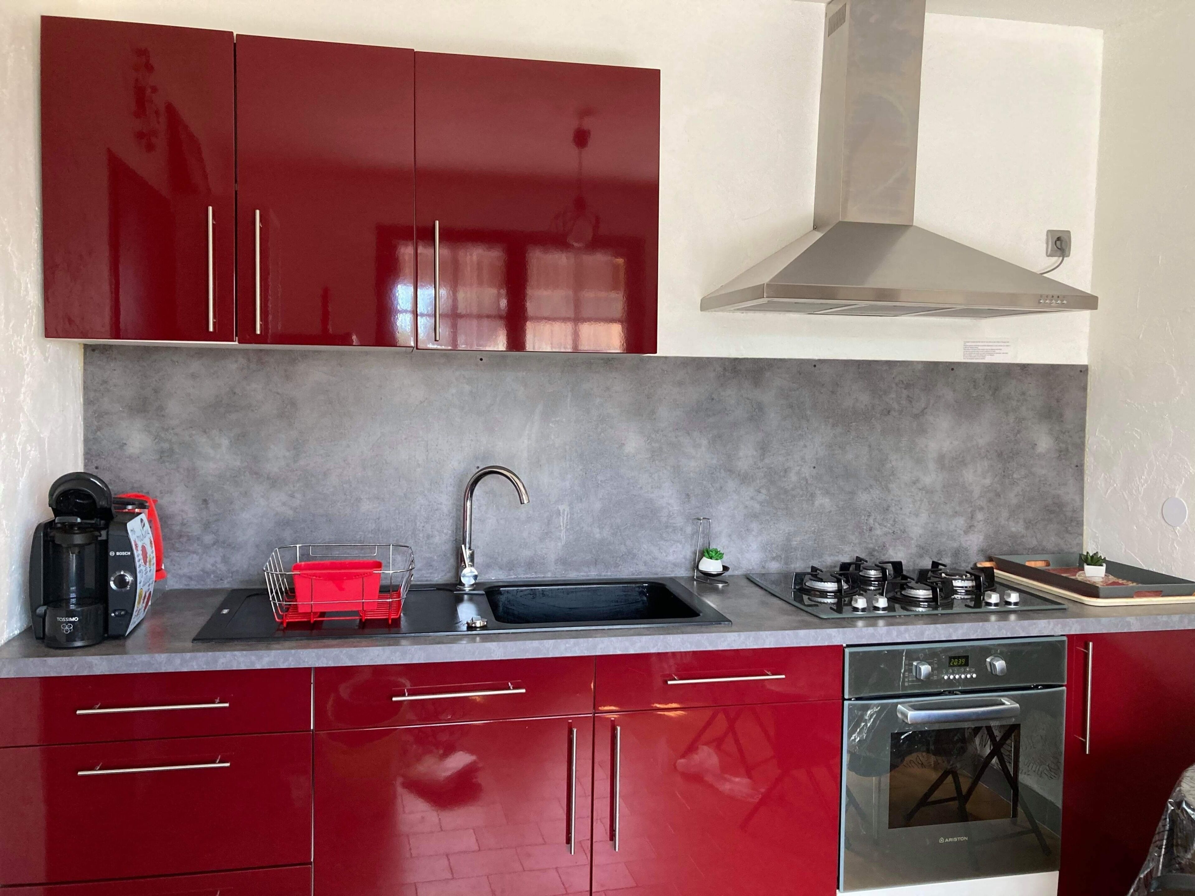 A kitchen with red cabinets, a Bosch coffee maker, a sink, and a stove.