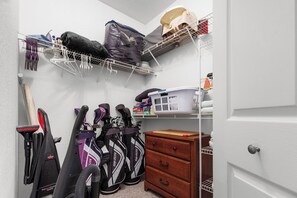 A storage closet with shelves, a vacuum cleaner, and golf bags. - 2BR Getaway Steps from Disney (Kissimmee)