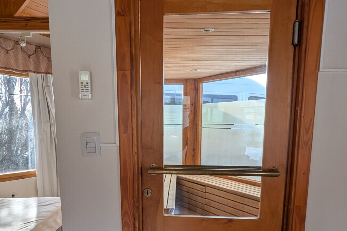 A wooden door with a metal handle, a small window, and a view of a balcony.