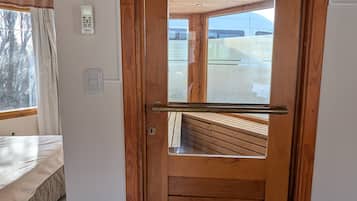 Een houten deur met een metalen handgreep, een klein raam en uitzicht op een balkon.