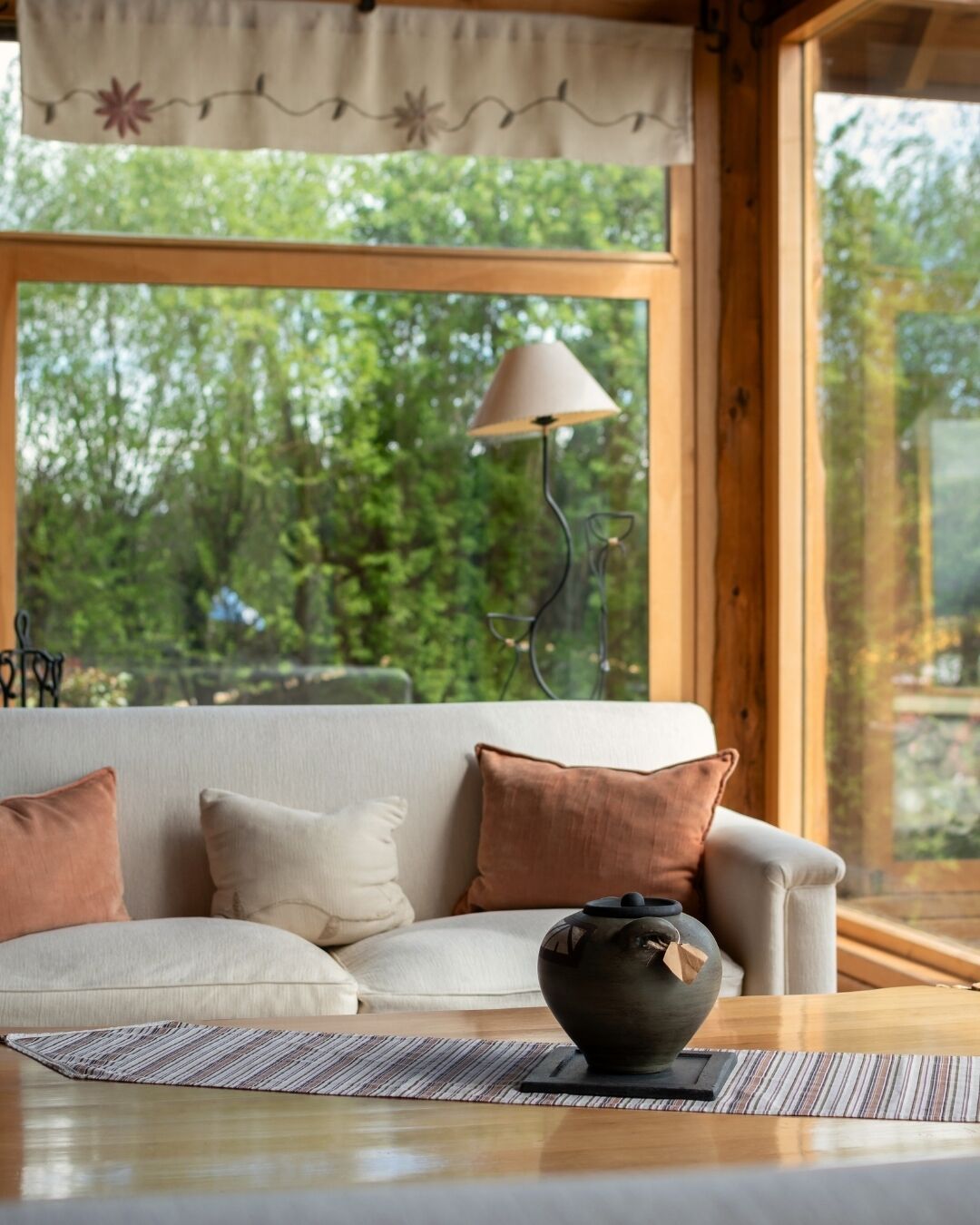 A cozy room with a sofa, a lamp, and a view of greenery outside.