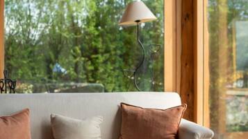 A cozy room with a sofa, a lamp, and a view of greenery outside.