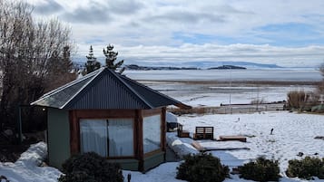 A small cabin with a sloped roof, a glass door, and a view of a snowy landscape.