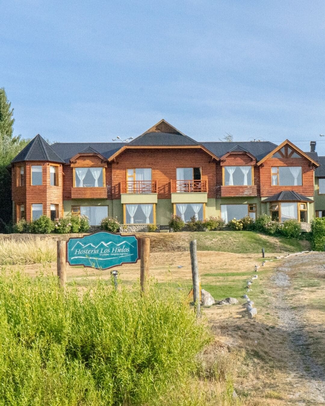 A row of wooden cabins with balconies, a sign in front, and a grassy area.