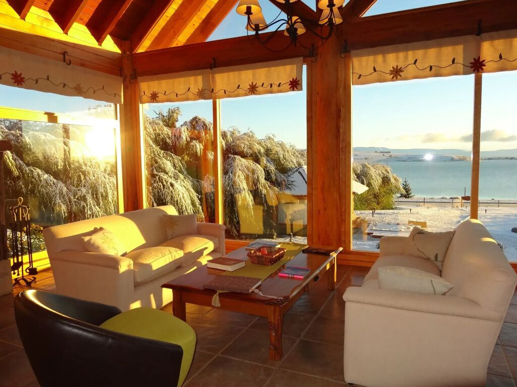 A sunlit room with a view of the beach, featuring a sofa, a coffee table, and a lamp.