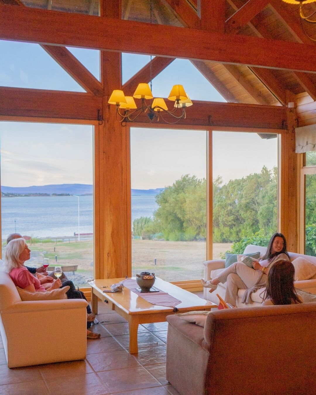 Une pièce spacieuse avec de grandes fenêtres, un plafond en bois et une table entourée de chaises.