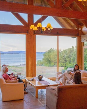 A spacious room with large windows, a wooden ceiling, and a table with chairs. - Hostería Los Hielos (El Calafate)