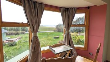 Une pièce avec vue sur un champ verdoyant, une chaise en bois et une table avec un plateau.