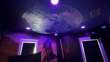 A room with a bed, a ceiling mural, and two wall-mounted lights.