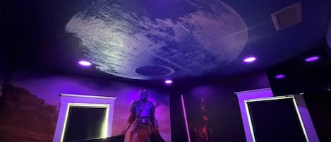 A room with a bed, a ceiling mural, and two wall-mounted lights.