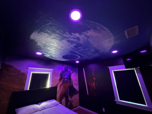 A room with a bed, a ceiling mural, and two wall-mounted lights.