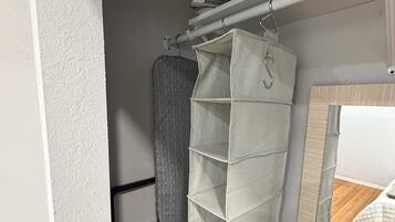 A storage unit with multiple compartments, a shower curtain, and a box labeled 'First Aid' on a shelf.