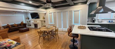 Una sala de estar moderna con chimenea, un comedor con mesa redonda y una cocina con una isla grande.