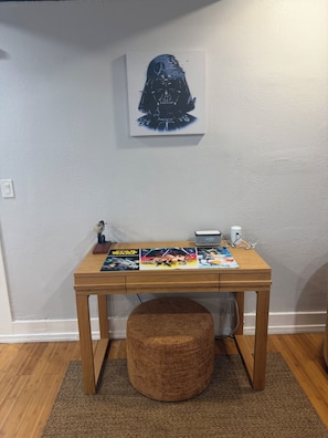 A wooden desk with a Star Wars-themed poster, a clock, and a small figurine.