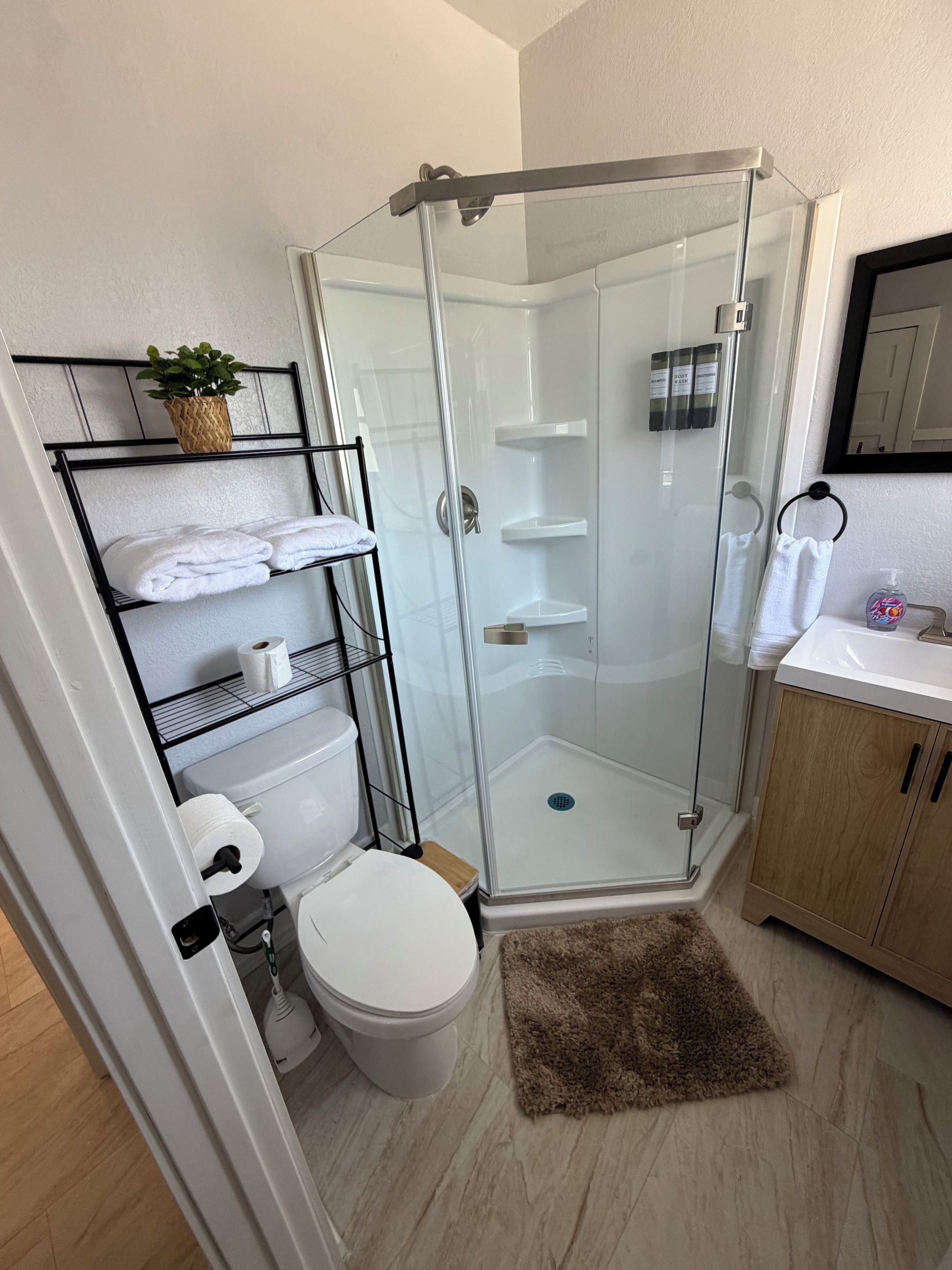 A modern bathroom with a glass shower enclosure, a toilet, a sink, and a towel rack.