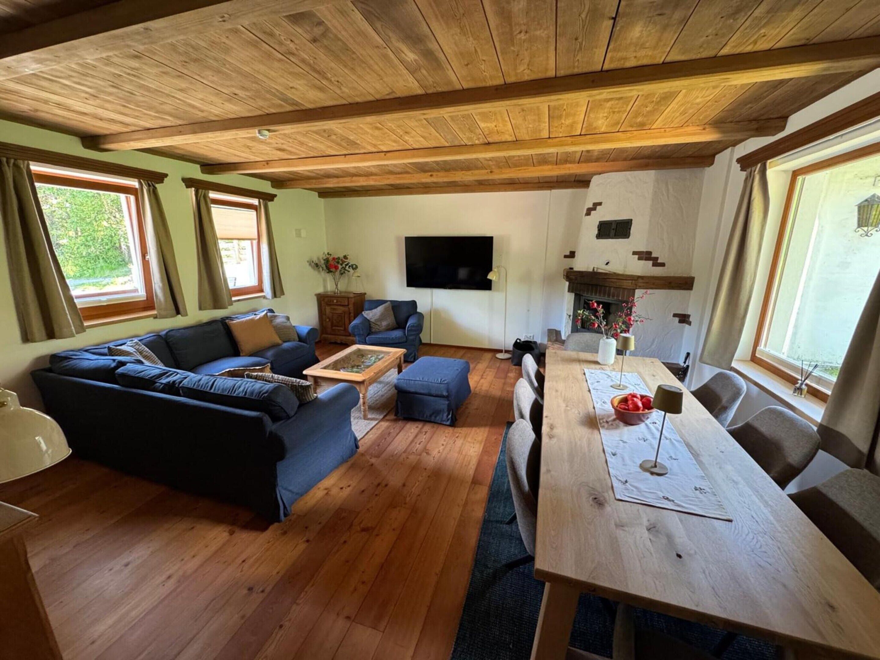A living room with a wooden ceiling, a sofa set, a coffee table, a TV, and a fireplace.
