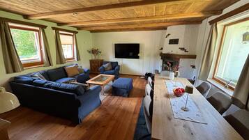 A living room with a wooden ceiling, a sofa set, a coffee table, a TV, and a fireplace.