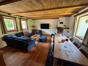 A living room with a wooden ceiling, a sofa set, a coffee table, a TV, and a fireplace.