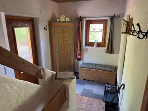 A staircase leading to a room with a wooden bench, a window with curtains, and a door with a fire extinguisher.