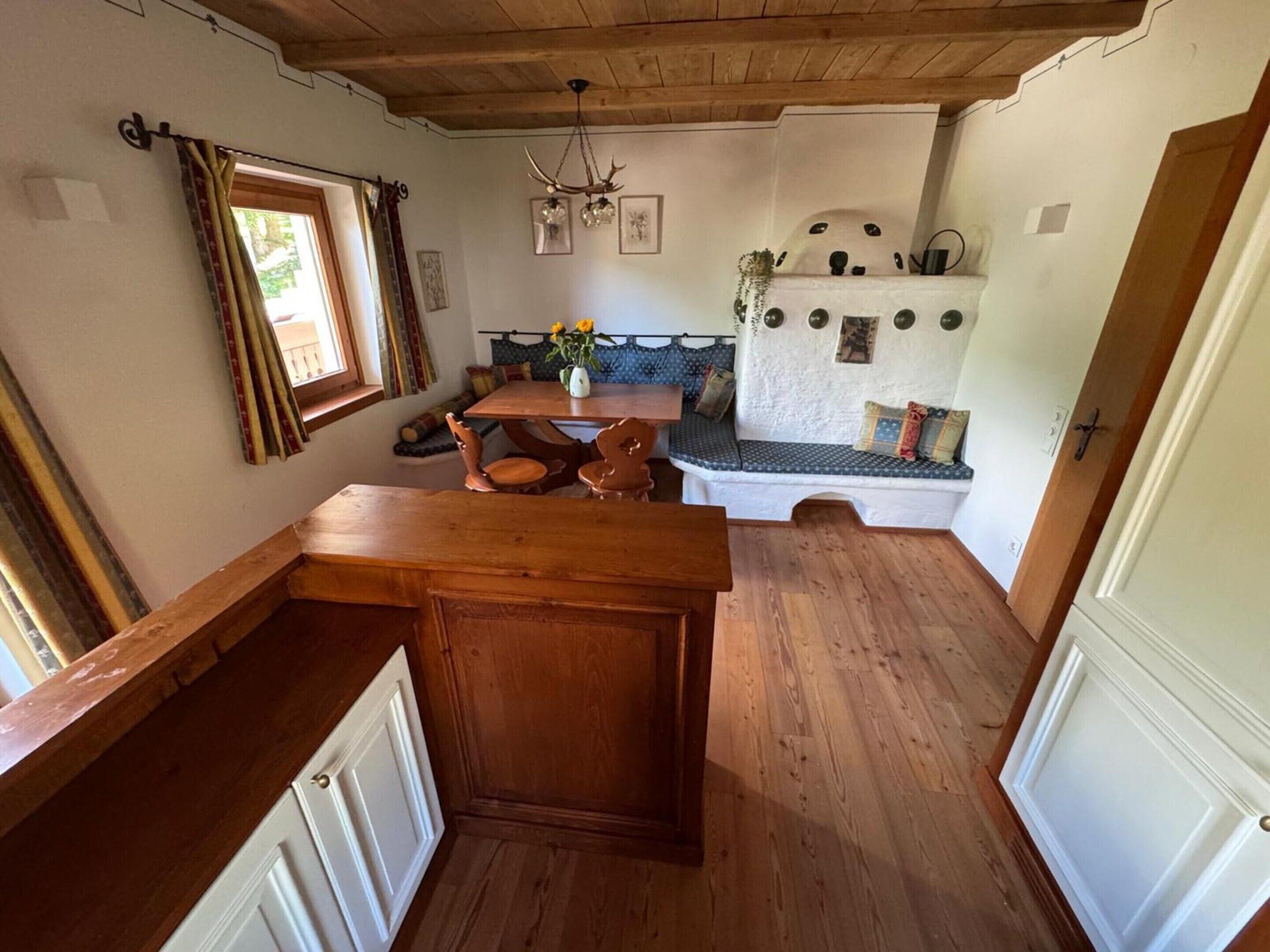 A cozy kitchen with wooden cabinets, a dining table, and a built-in bench with cushions.