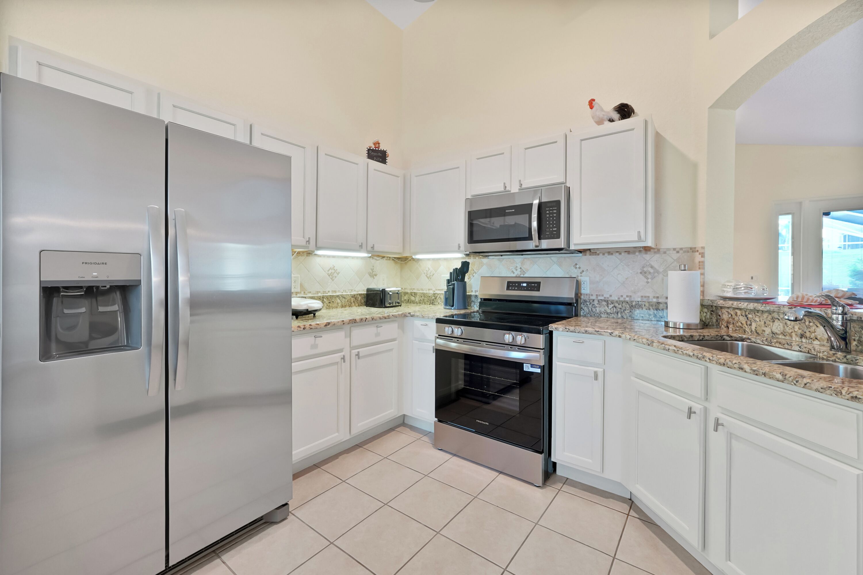 A modern kitchen with white cabinets, stainless steel appliances, and a tiled backsplash.