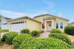 A residential house with a garage, a front porch, and a well-maintained lawn. - Luxury 4 br Golf Villa, Minutes to Disney, pool (Davenport)