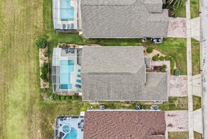 An aerial view of a residential area with a house featuring a swimming pool, a garage, and a well-maintained lawn. - Luxury 4 br Golf Villa, Minutes to Disney, pool (Davenport)