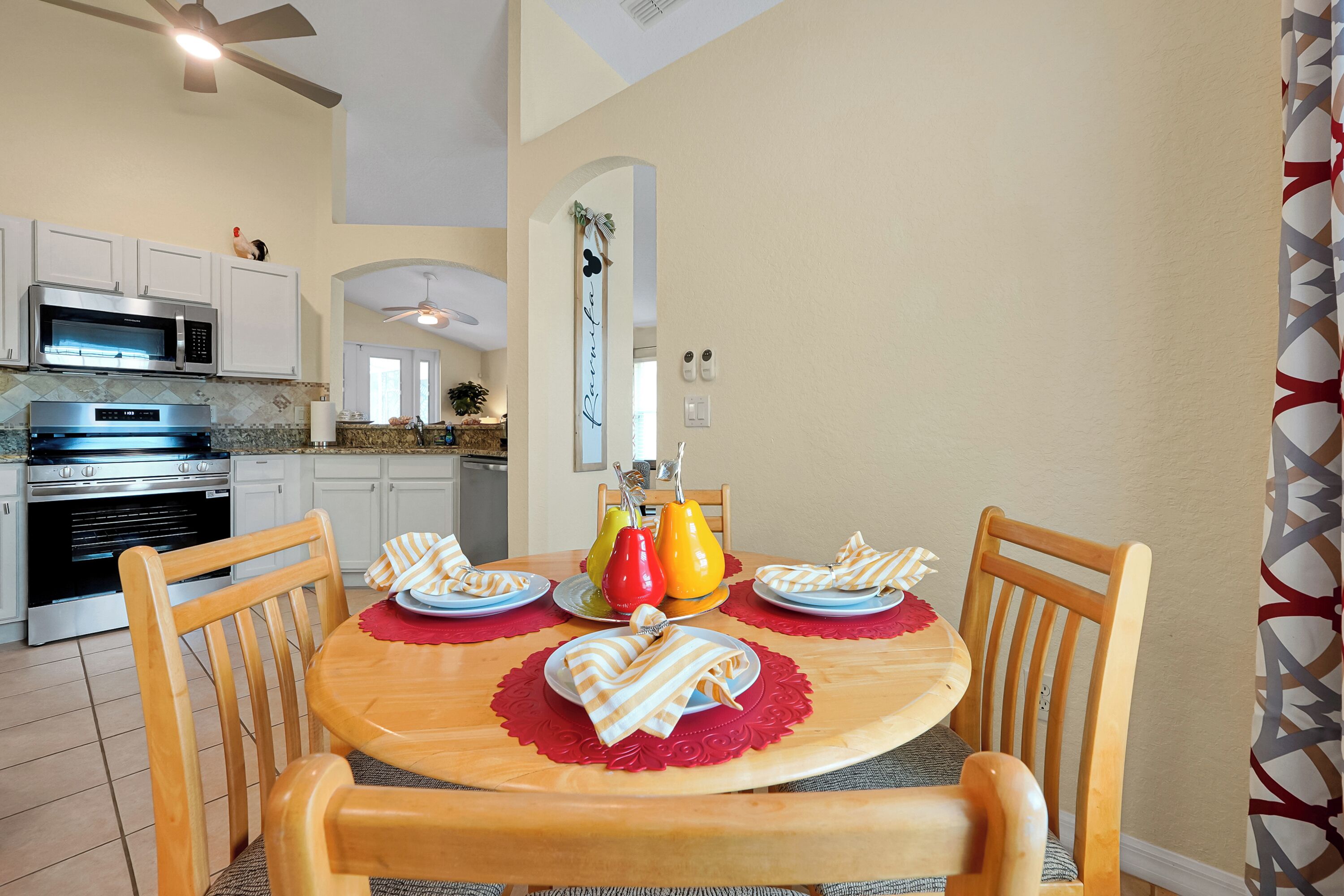 A dining area with a round table, chairs, and a kitchen in the background.