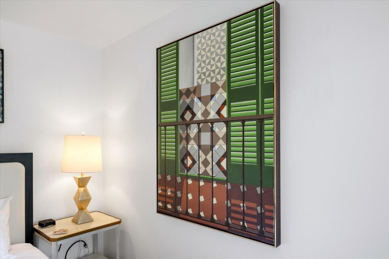 Habitación de hotel con cama, mesita de noche con lámpara y una gran obra de arte abstracta en la pared.