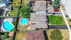An aerial view of a residential area with two swimming pools, a red car, and a street. - Cozy 3BR Barrie Home Near Snow Valley Lake & Downtown (Barrie)