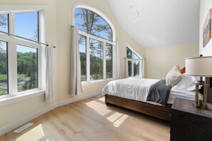 Una camera da letto con un letto grande, diverse finestre e un soffitto a falde.