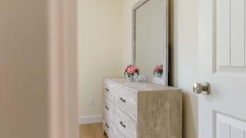 A room with a wooden dresser, a mirror, and a door with a round handle.