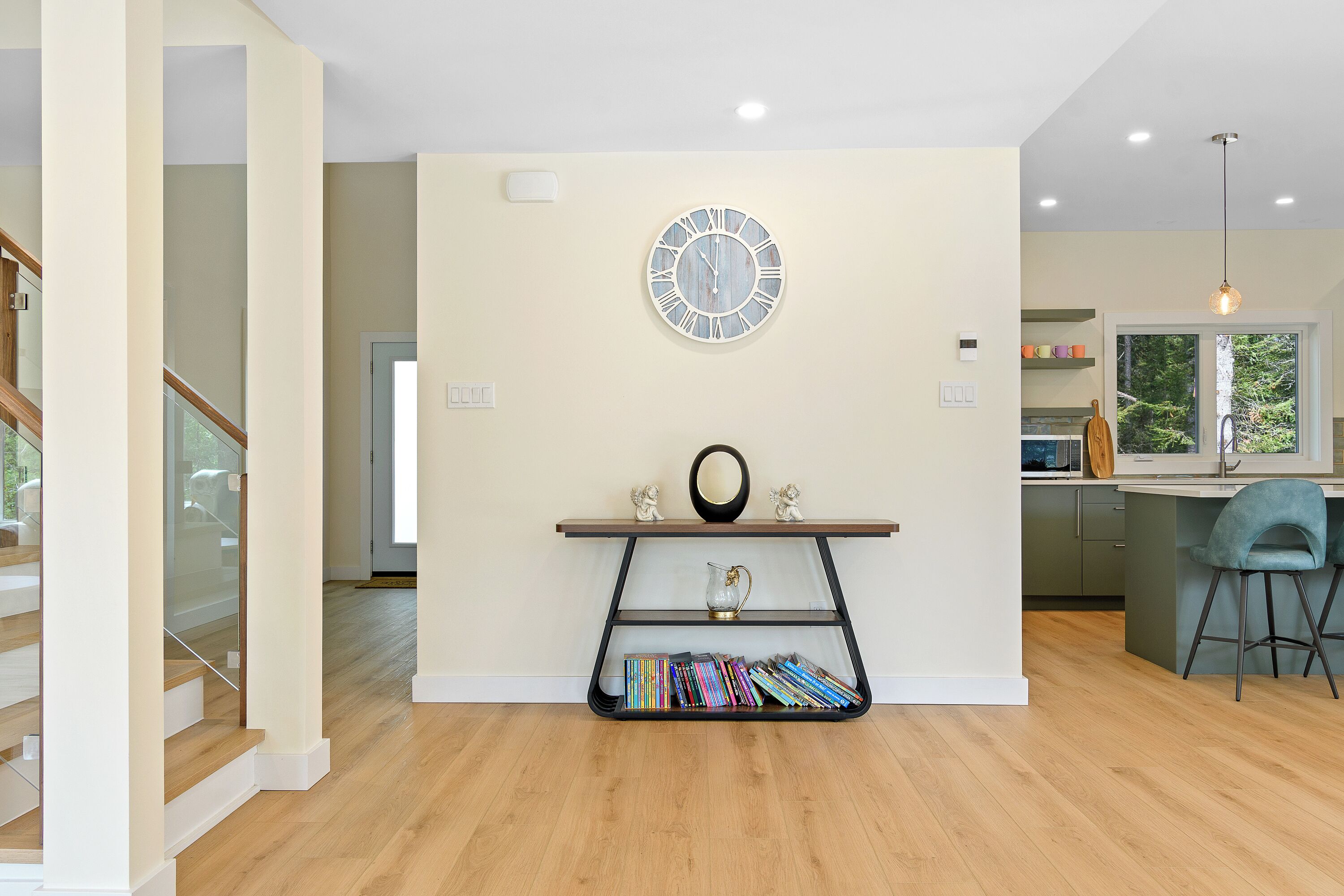 Una cocina moderna con una isla integrada, un reloj en la pared y una estantería llena de libros.