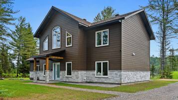 A two-story house with a stone foundation, large windows, and a covered porch.