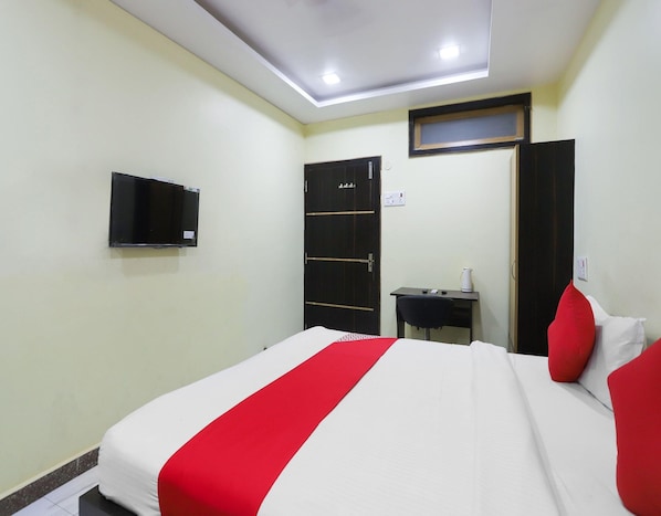 A hotel room with a bed, a desk, a television, and a wardrobe.