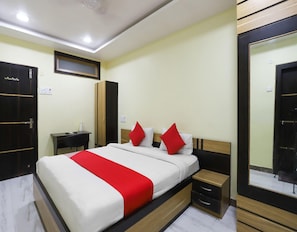 A hotel room with a bed, bedside tables, a desk, and a wardrobe.