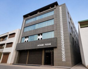 Un edificio de varios pisos con el nombre 'AKHAND PARAM' en la fachada.