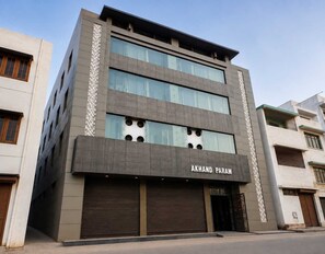 A multi-story building with a modern facade, featuring a prominent sign reading 'AKHAND PARAM' on the ground floor.