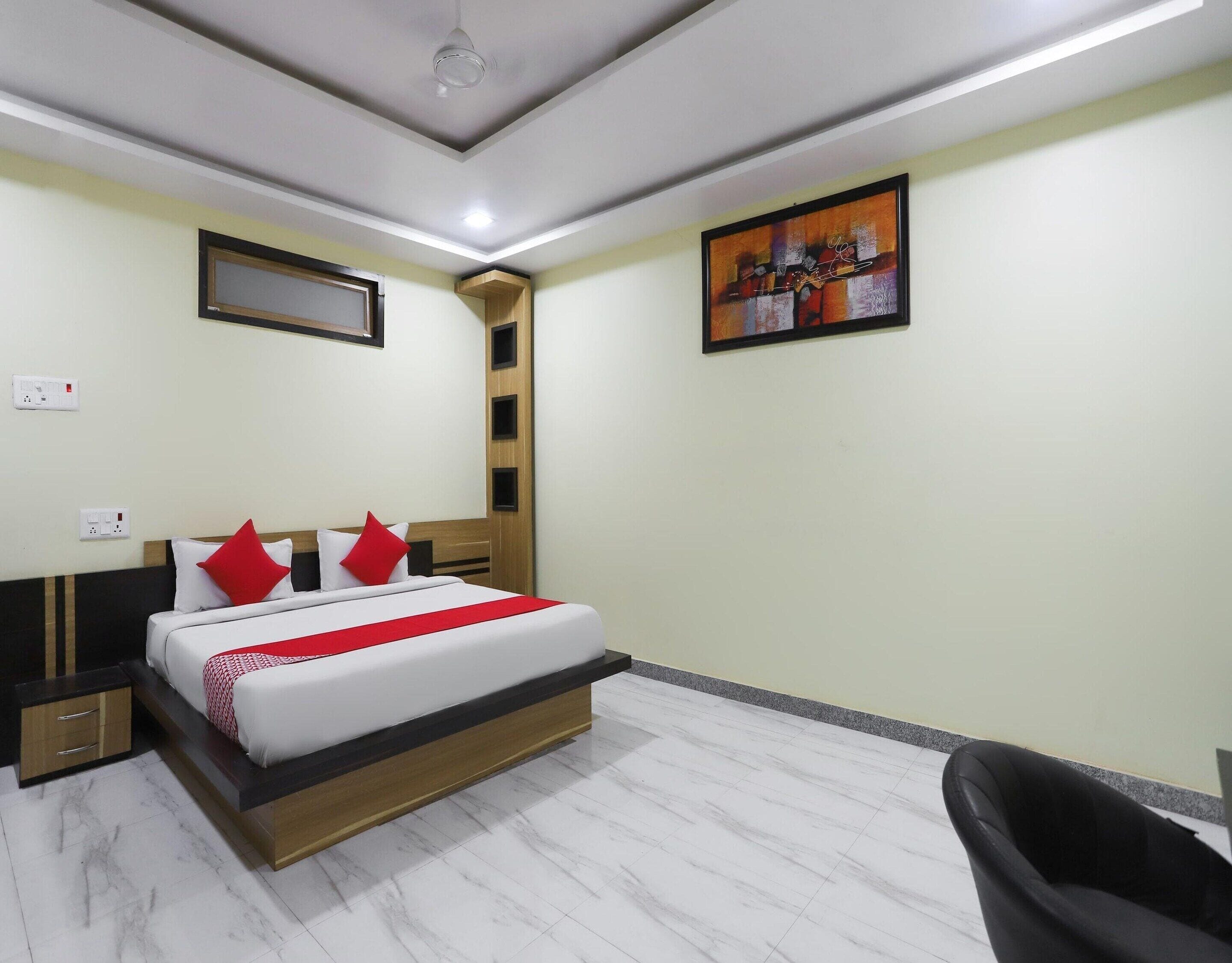 A hotel room with a bed, bedside tables, a chair, a painting on the wall, and a ceiling light.