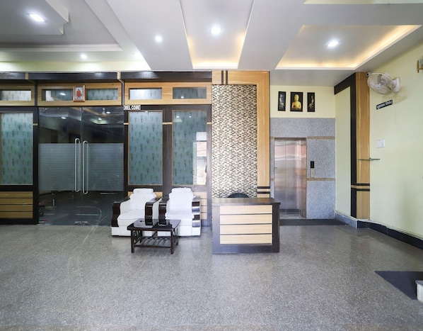 A reception area with a reception desk, seating area, and a wall-mounted elevator.