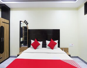 A hotel room with a bed, a wardrobe, a mirror, and a bedside table with a phone. - Deluxe Akhand Param (Begusarai)