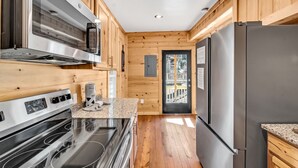 Een keuken met houten wanden, roestvrijstalen apparatuur en een granieten aanrecht.