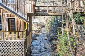 A wooden cabin with a balcony overlooking a stream.
