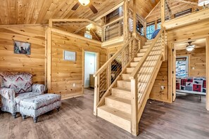 A wooden interior with a staircase, a couch, and a quilted blanket.
