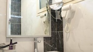 Casa de banho com uma pia branca, um espelho, um secador de cabelo e um telefone.