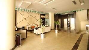 Um lobby moderno com balcão de recepção, área de estar e um espelho grande.