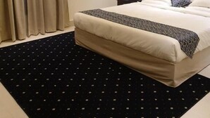 Habitación de hotel con una cama grande, una mesita de noche con lámpara y un tapete con diseño blanco y negro.