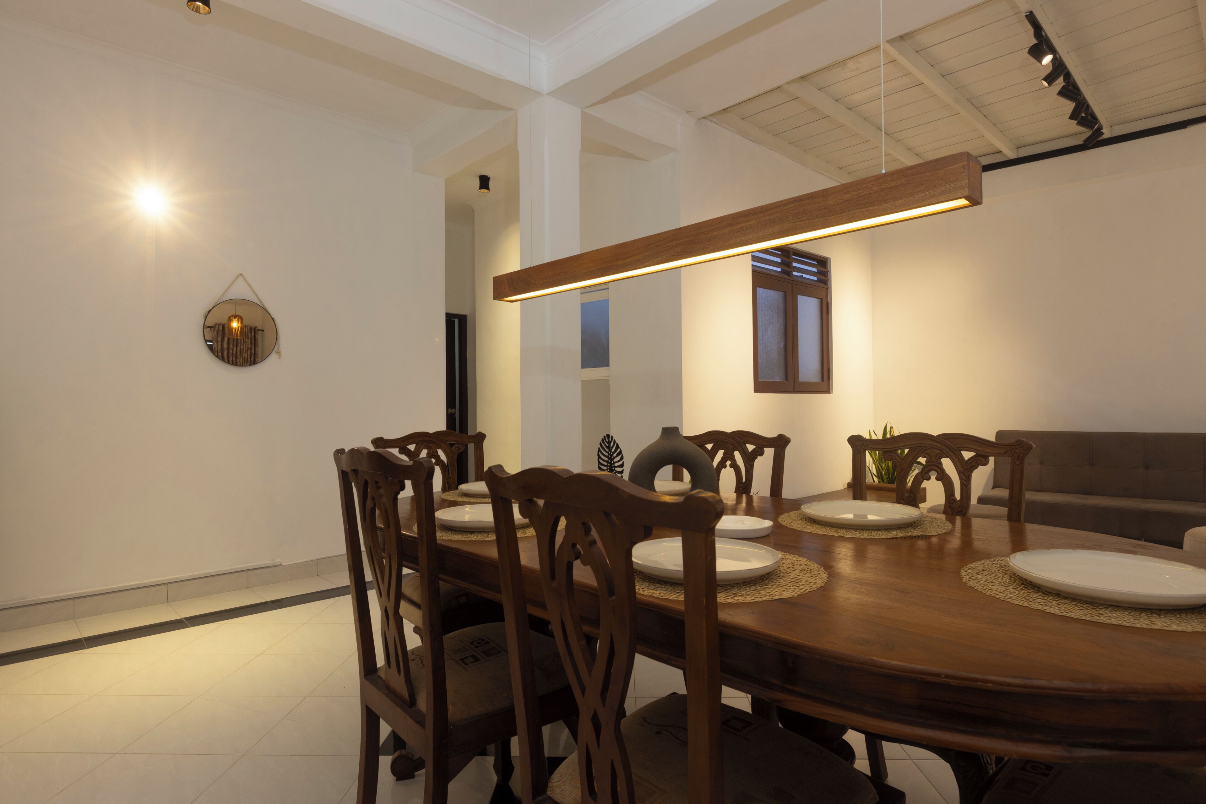 A dining area with a wooden table, chairs, and a hanging light fixture.