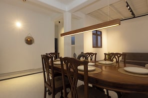 Un comedor con una mesa de madera, sillas y una lámpara colgante.