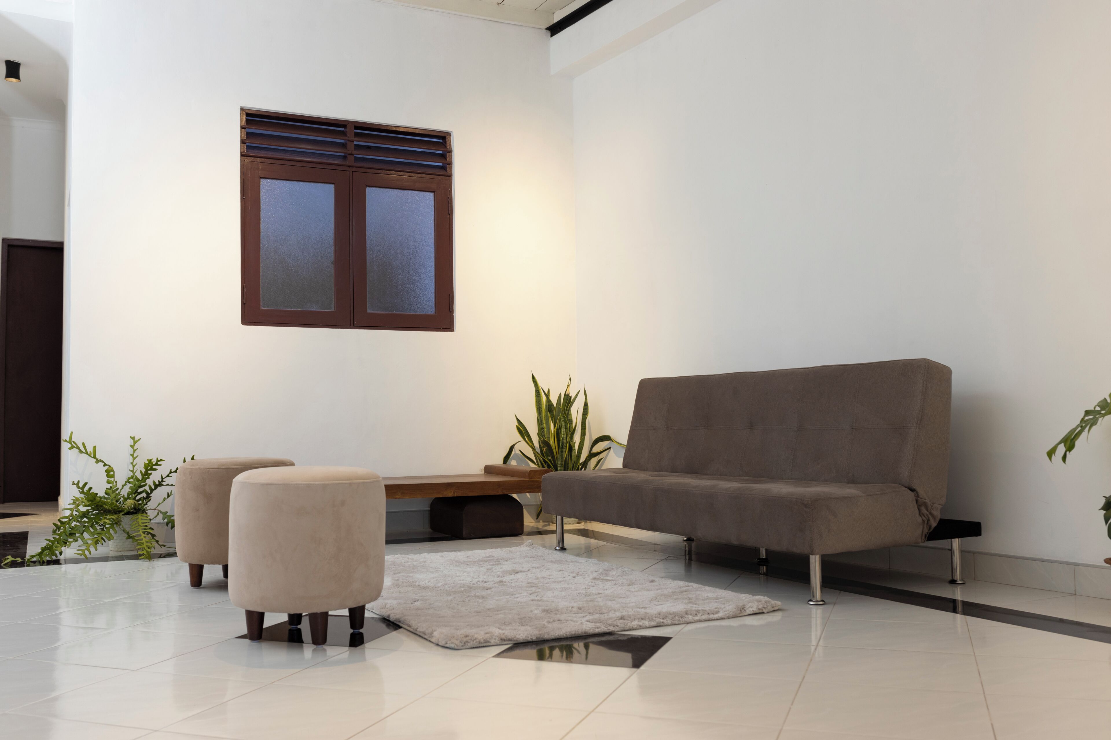 A modern living room with a sofa, ottomans, a small table, and a potted plant.